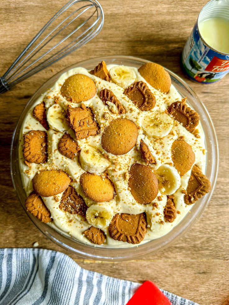 a dessert dish with cookies and cream in it on a table next to a whisk