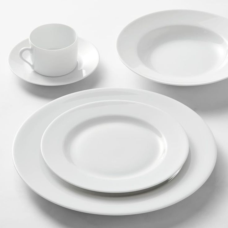 three white plates and two cups on a table