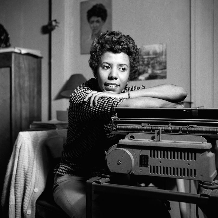 black and white photograph of a woman leaning on an old typewriter in her living room