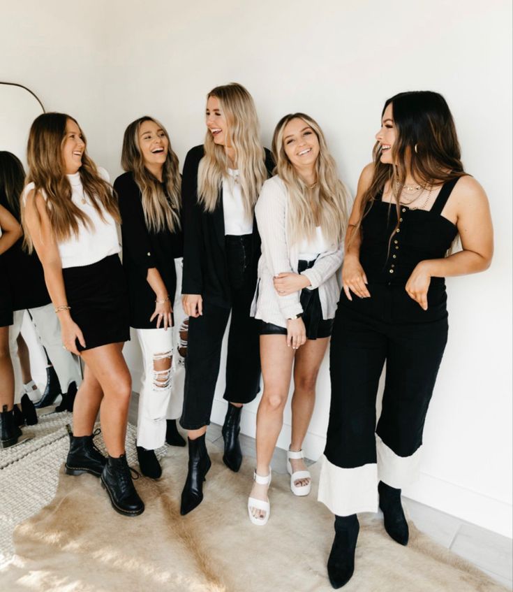 four women standing next to each other in black and white outfits