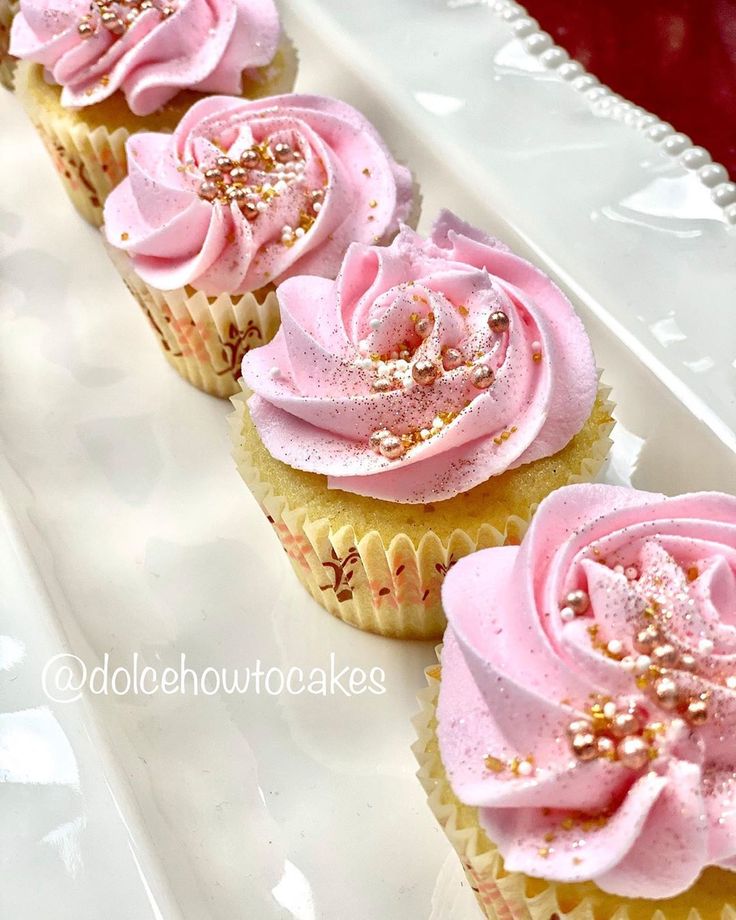 cupcakes with pink frosting and sprinkles on a white plate