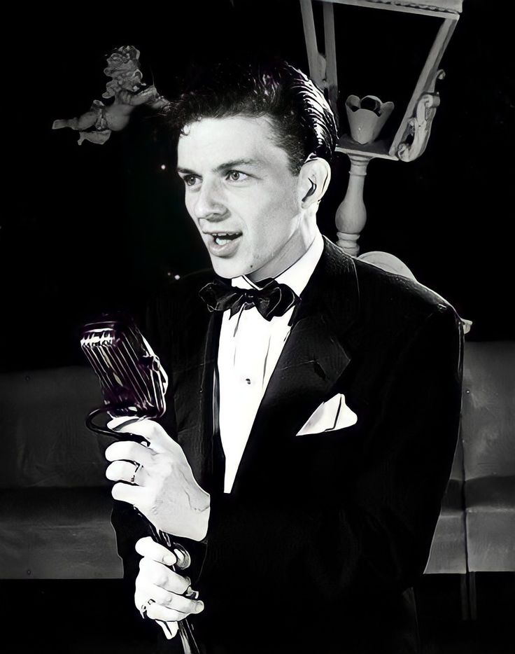 a man in a tuxedo holding a hair dryer