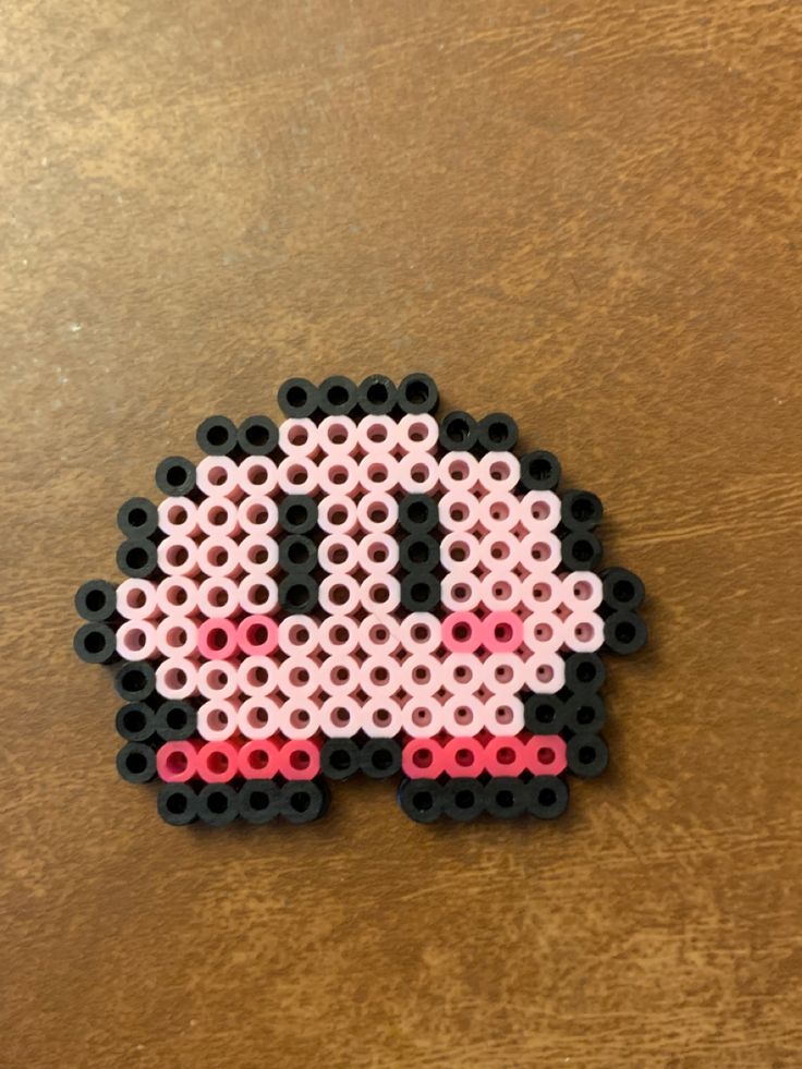 a piece of art made to look like an old school computer game console controller with pink and black beads