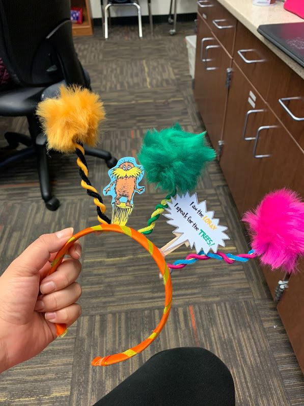 someone is holding some colorful hair accessories in an office cubicle with chairs and desks behind them