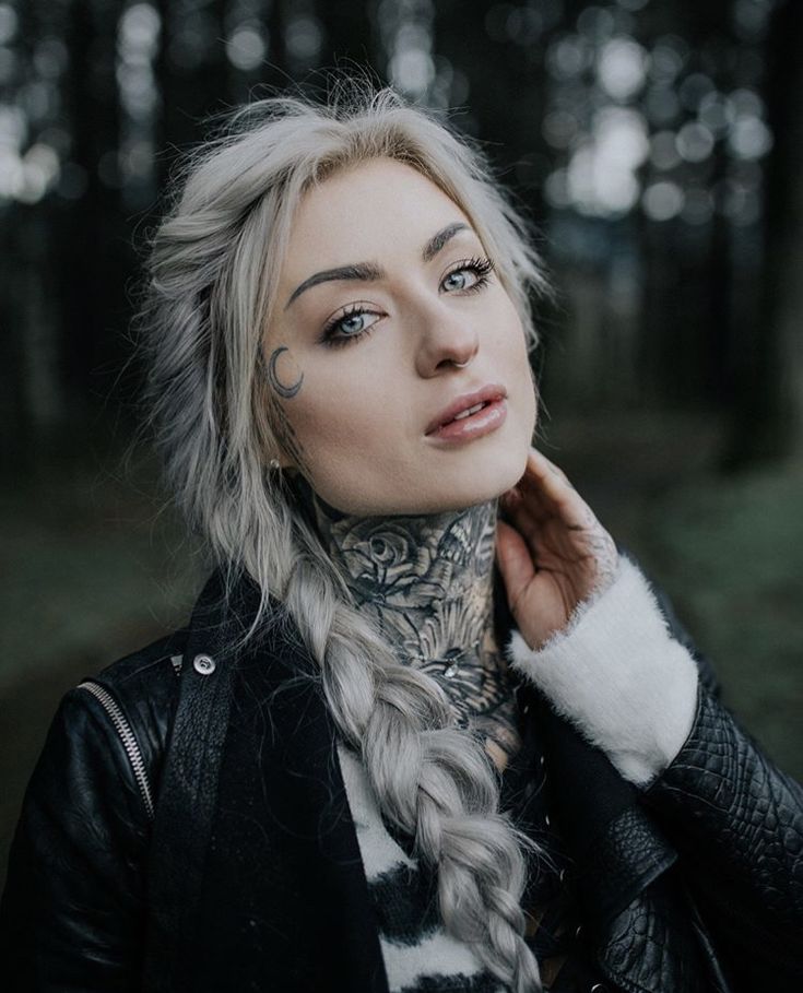 a woman with long hair and tattoos on her neck is looking up at the camera