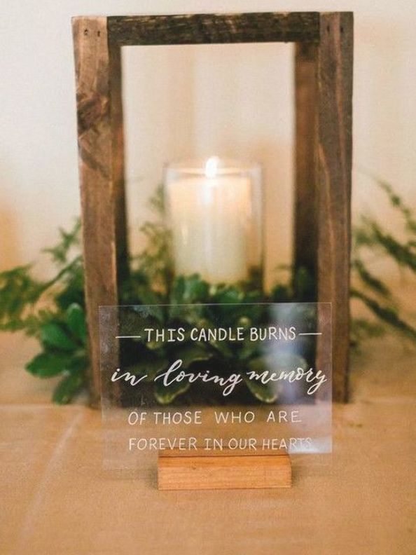 a wooden frame with a candle and some plants in it on top of a table