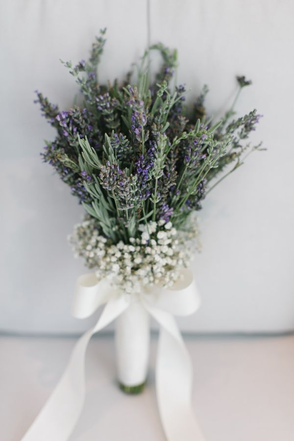 a bouquet of lavenders and baby's breath tied to a white ribbon on a table