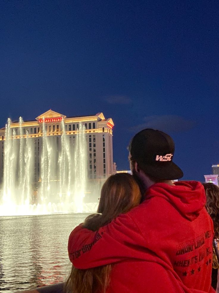 a man and woman are looking at the fountains in las vegas