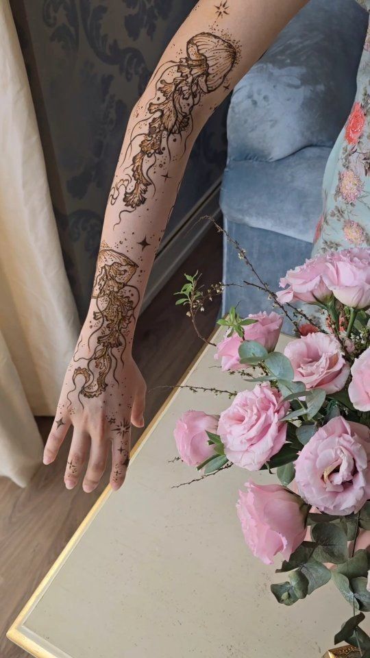 a woman's arm with hendix on it and flowers in the vase