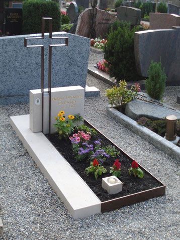 a grave with flowers and candles in the ground next to some headstones on either side