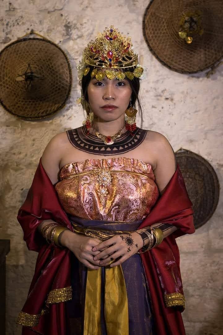 a woman dressed in an elaborately designed costume and headdress, posing for the camera