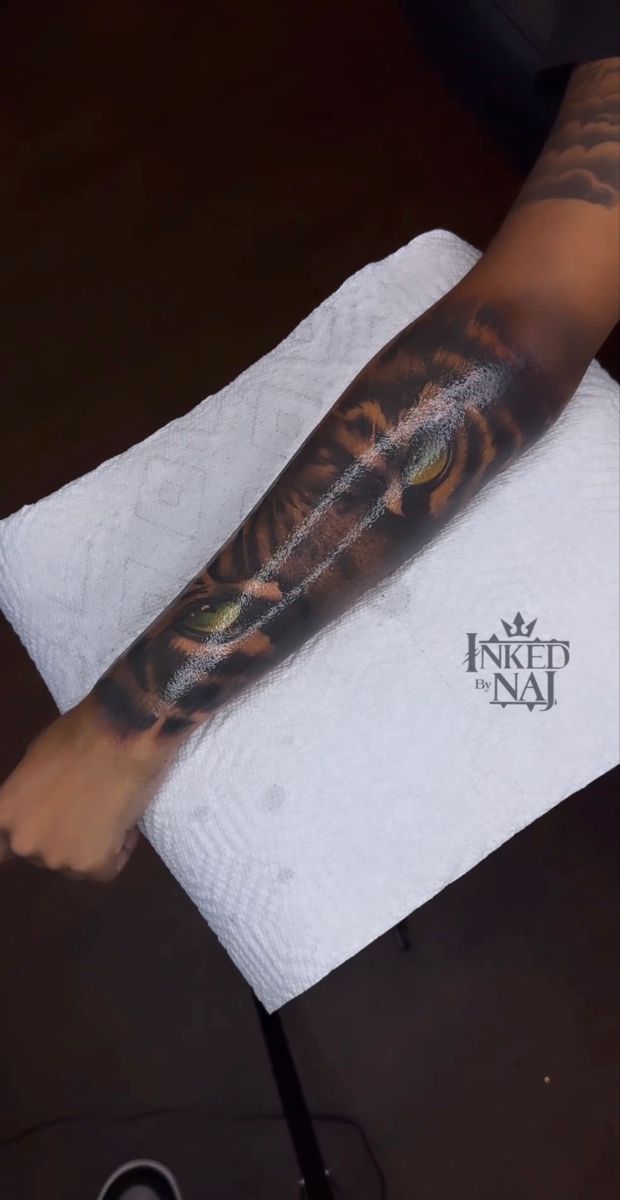 a person with a tiger tattoo on their arm and leg is holding a white towel