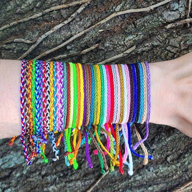 a woman's arm with several different colored bracelets on top of each other