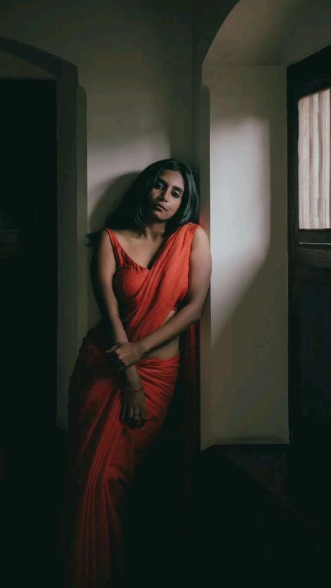 a woman in an orange dress leaning against a wall