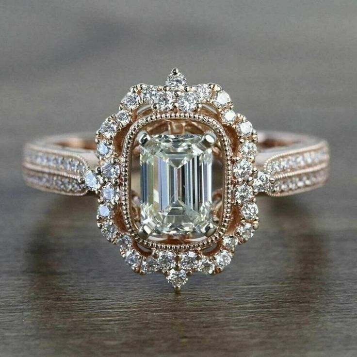 an emerald and diamond ring on a wooden table