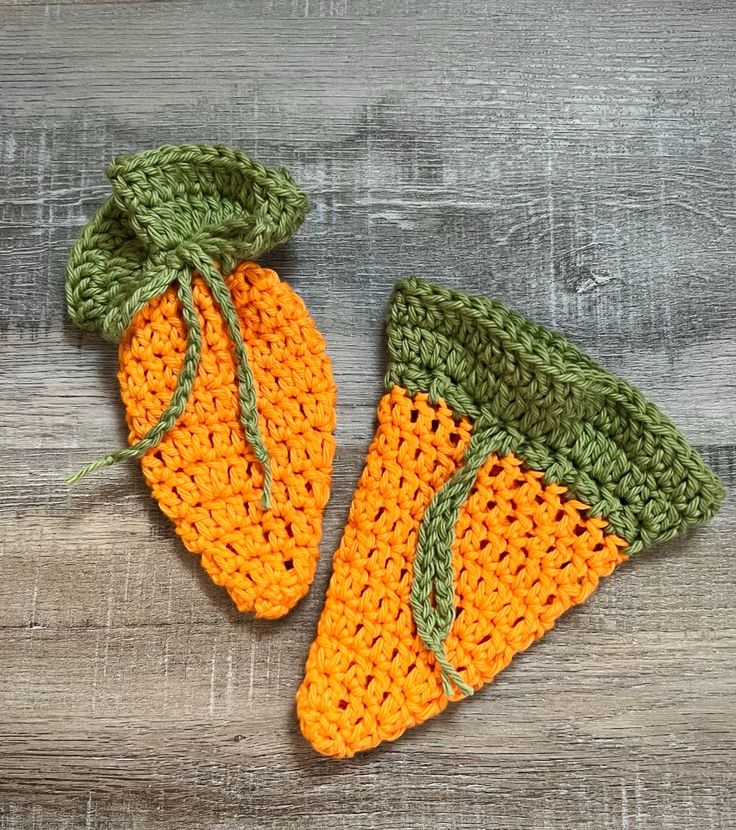 two crocheted carrots sitting on top of a wooden table