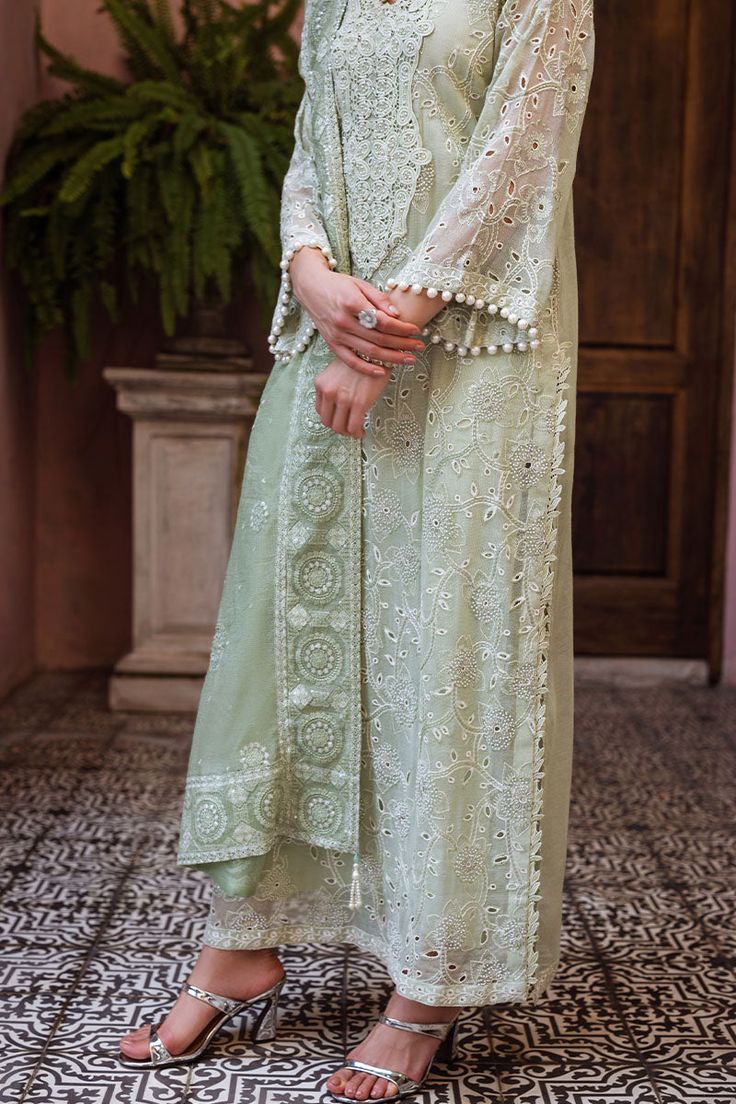 Dhara, a luxurious ensemble featuring a chikankari embroidered shirt adorned with a milky lace and pearl accents. The look is complete with a dupatta, featuring chikankari embroidery, light sequins, and pearl tassels thus adding a touch of elegance. This is a 3 pc outfit. Elegant Designer Mulmul Palazzo Set, Pista Green Mulmul Palazzo Set For Wedding, Elegant Mulmul Palazzo Set With Dupatta, Elegant Pista Green Traditional Wear With Naqshi, Pista Green Chikankari Embroidered Palazzo Set In Mulmul, Pista Green Chikankari Embroidered Mulmul Sharara, Pista Green Mulmul Sharara With Chikankari Embroidery, Semi-stitched Pista Green Kurta With Naqshi Detail, Pista Green Wedding Kurta With Naqshi Details