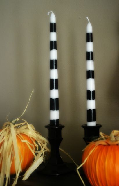 two black and white candles sitting next to each other on top of a table with pumpkins