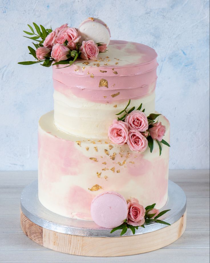 a three tiered cake with pink and white frosting, flowers on the top