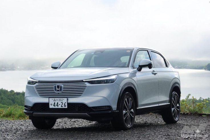 a silver car parked on top of a gravel road next to a body of water