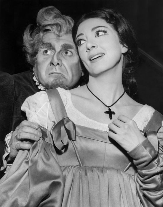 an old black and white photo of a woman holding a man's face in front of her