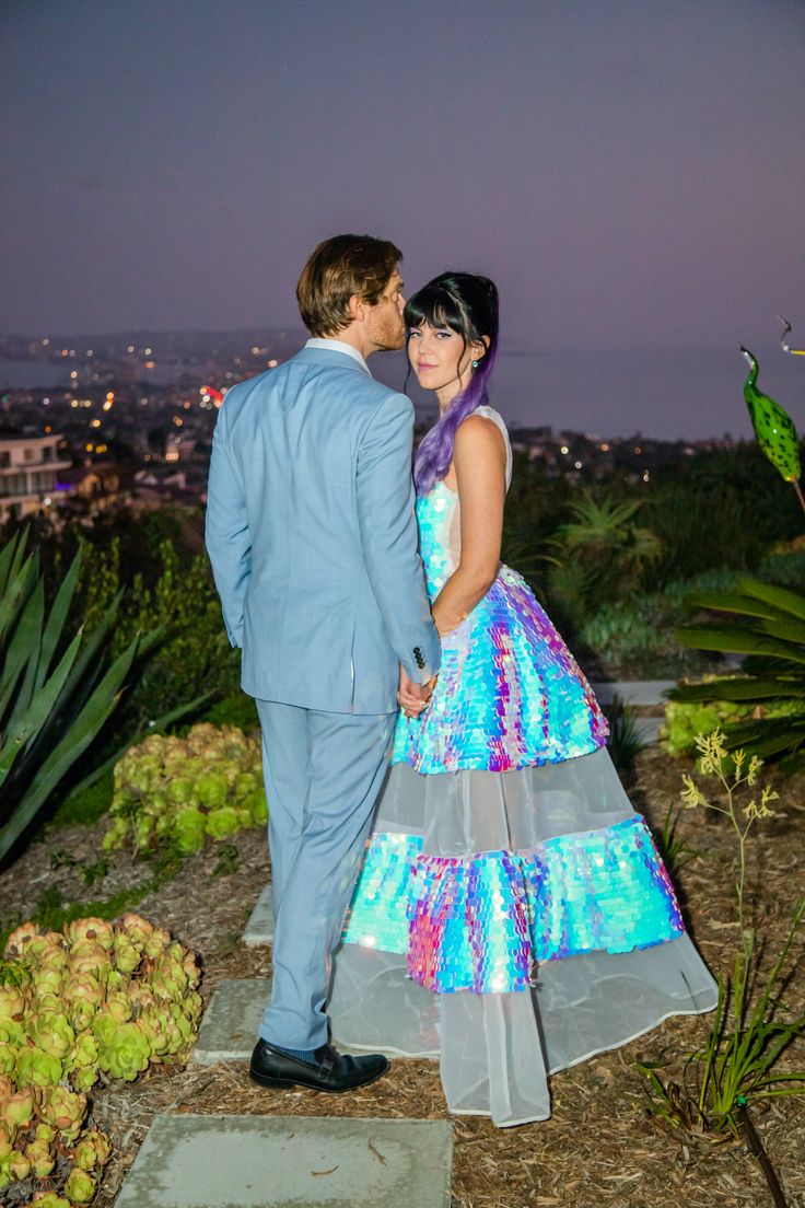 a young man and woman dressed in formal wear standing next to each other near cactus plants