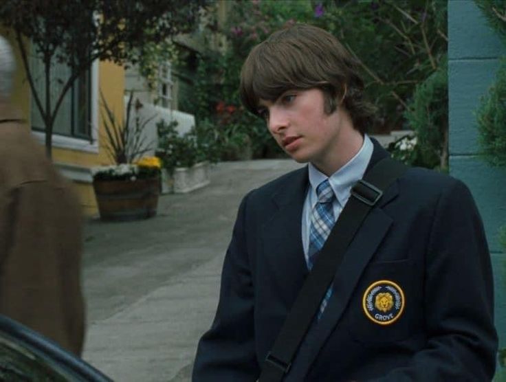 a young man in a suit and tie standing next to a car on the street