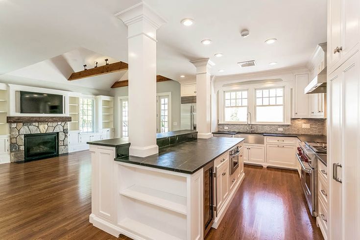 a large kitchen with white cabinets and black counter tops, along with hardwood flooring