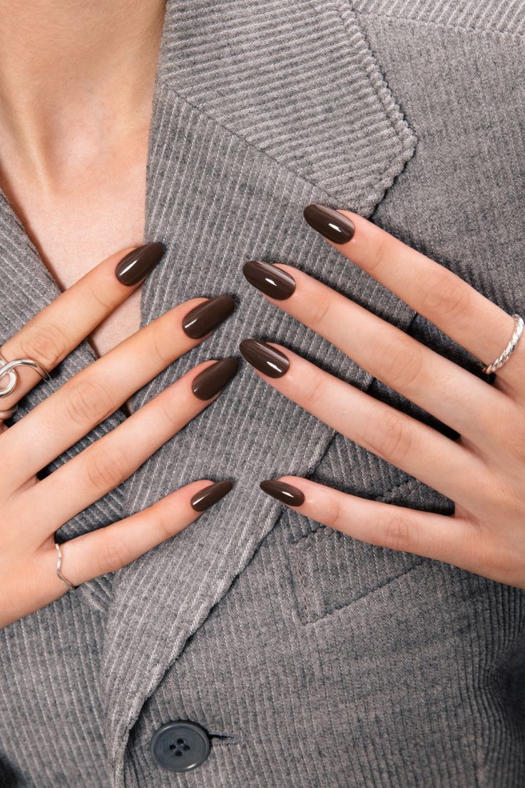 a woman's hands with brown manies and rings on her fingers, wearing a gray sweater