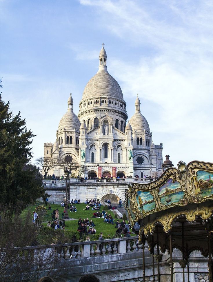 an ornately decorated carousel in front of a large white building with many spires