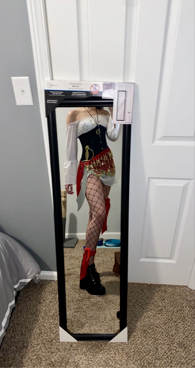 a woman dressed as a pirate standing in front of a mirror