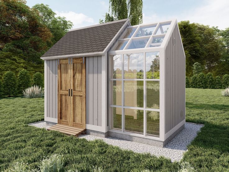 a small white shed with a wooden door and windows on the side, in a grassy area