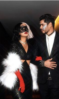 a man and woman dressed up in black with white feathers on their head, standing next to each other