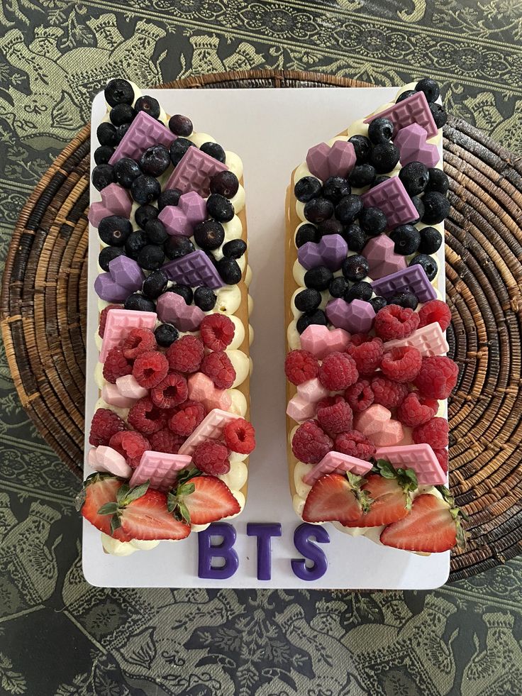 two slices of cake decorated with berries, strawberries and chocolate bars on a plate