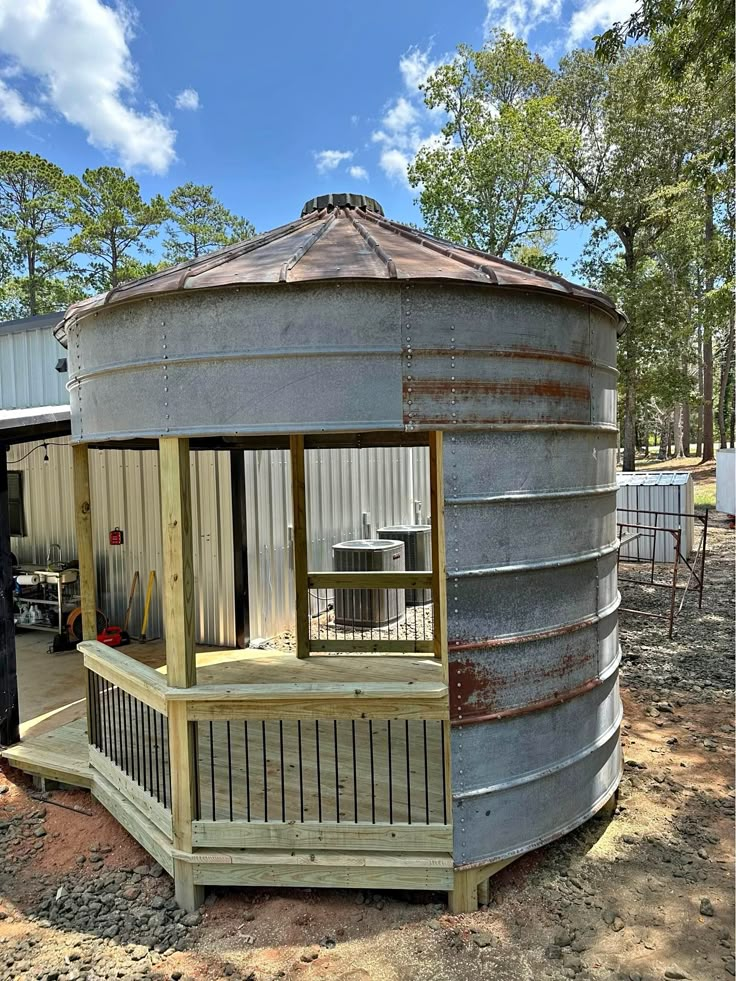 a round metal structure sitting on top of a dirt field