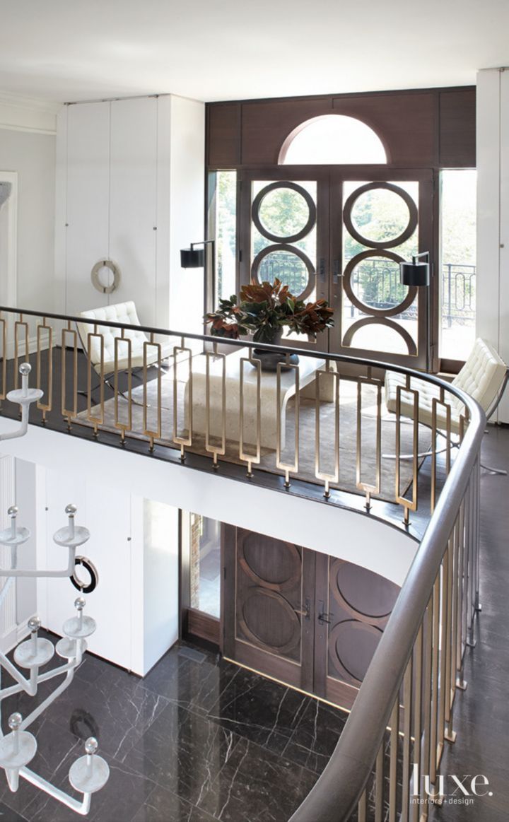 a staircase leading up to a living room with white walls and black marble flooring