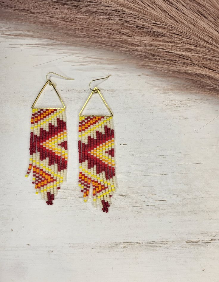 two pairs of beaded earrings on top of a wooden table next to some hair