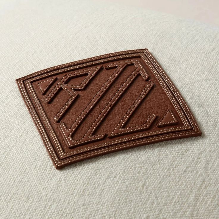 a close up of a brown leather patch on a white cloth material with stitching