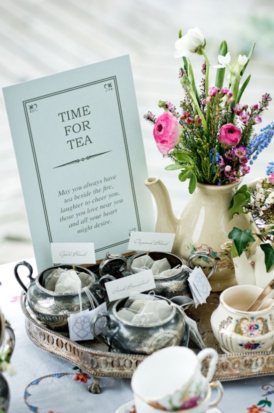 a table topped with tea cups and saucers next to a vase filled with flowers