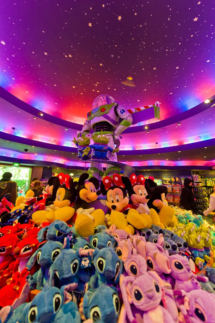 many stuffed animals are stacked on top of each other in front of a colorful ceiling