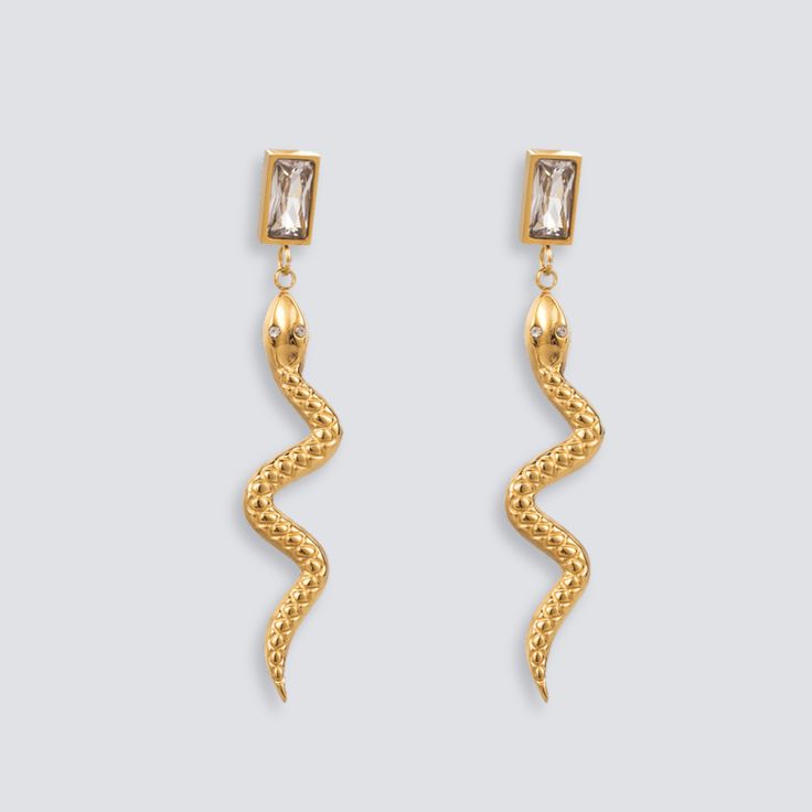 DESCRIPTION & DETAILS These earrings exude a sense of mystique and allure. With their curves and elegant form, they add a touch of exotic charm to any ensemble. Embrace your wild side with these statement pieces that are sure to turn heads wherever you go. Plating: 14k Gold Materials: 14k Gold on Stainless Steel, Moissanite Crystals Hypoallergenic SUSTAINABILITYIn-house plating - All pieces are hand crafted by our in-house jewellers ensuring a high standard of working conditions.Fair pricing - D Snake Shape Earrings For Party, Elegant Single Snake-shaped Earring, Elegant Snake Shaped Metal Jewelry, Long Snake, Snake Earrings, Recycled Sterling Silver, Gold Studs, Gold Material, Solid 925 Sterling Silver