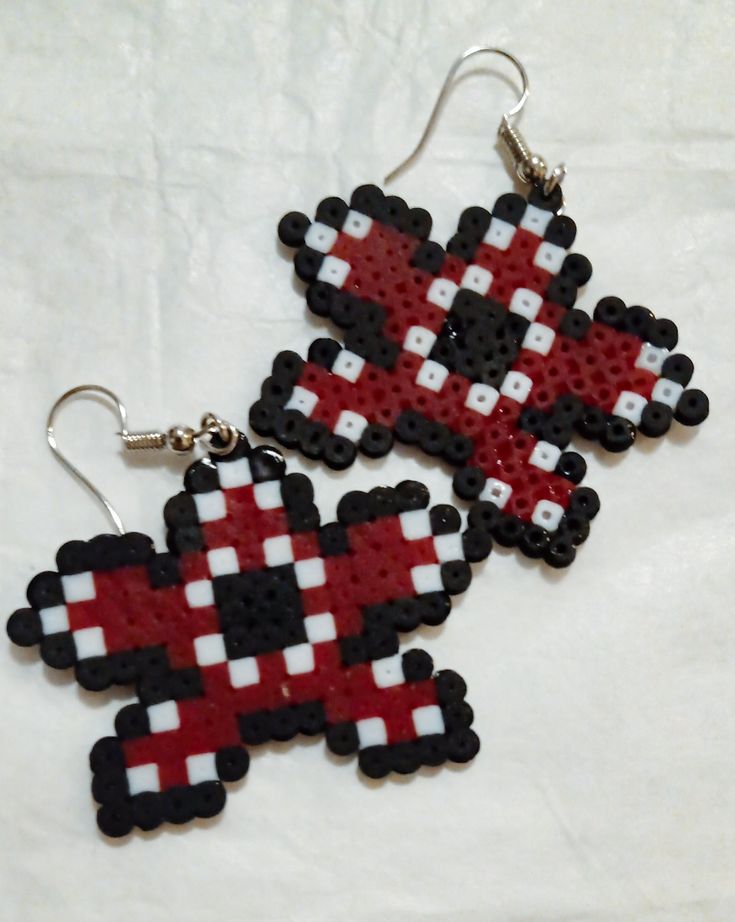 two cross stitched earrings sitting on top of each other