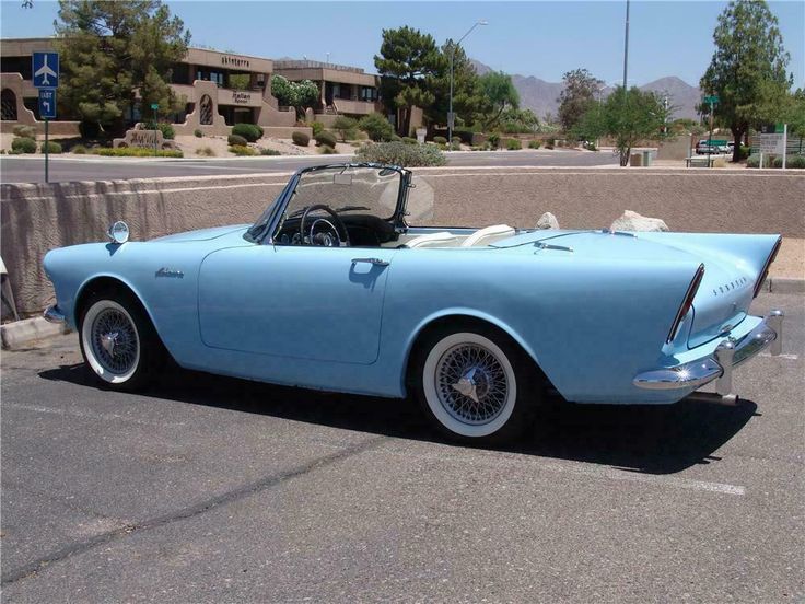 an old blue convertible car parked in a parking lot