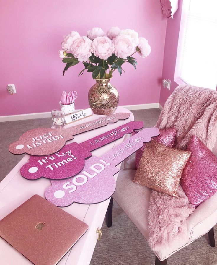 a room with pink walls and furniture in the corner, along with decorative signs that spell out i love you