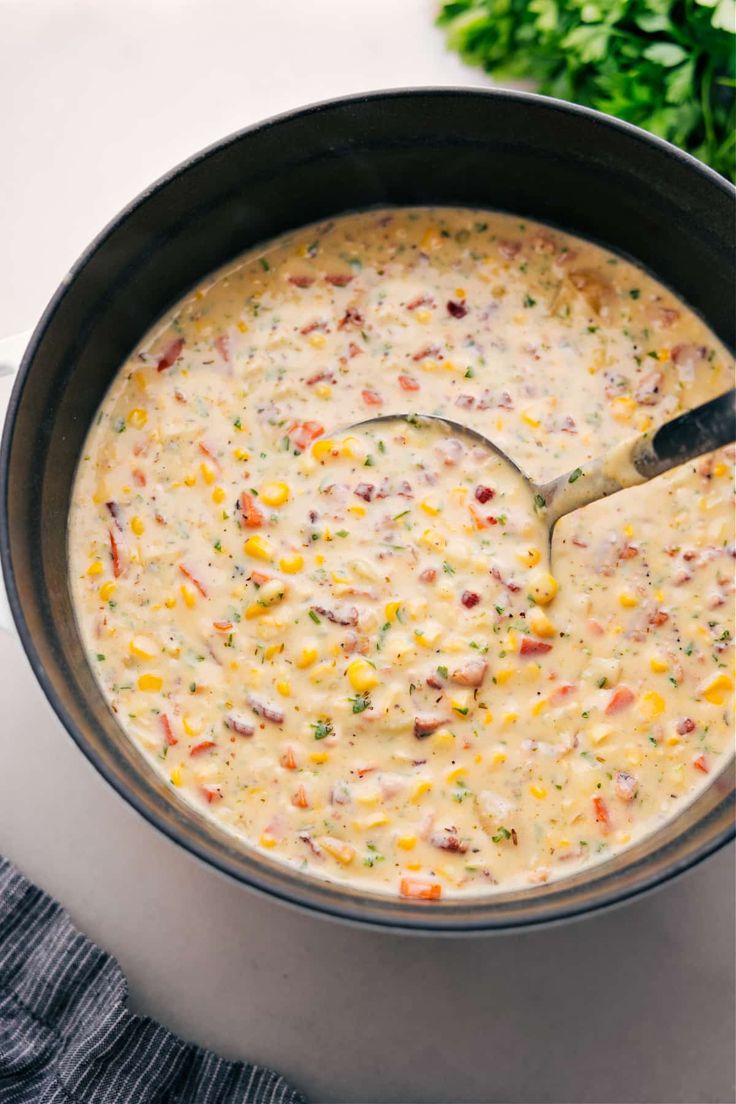 a large pot filled with corn chowder next to some parsley on the side