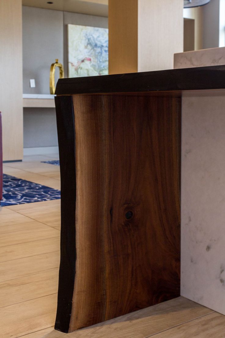 a wooden counter top sitting on top of a hard wood floor next to a vase