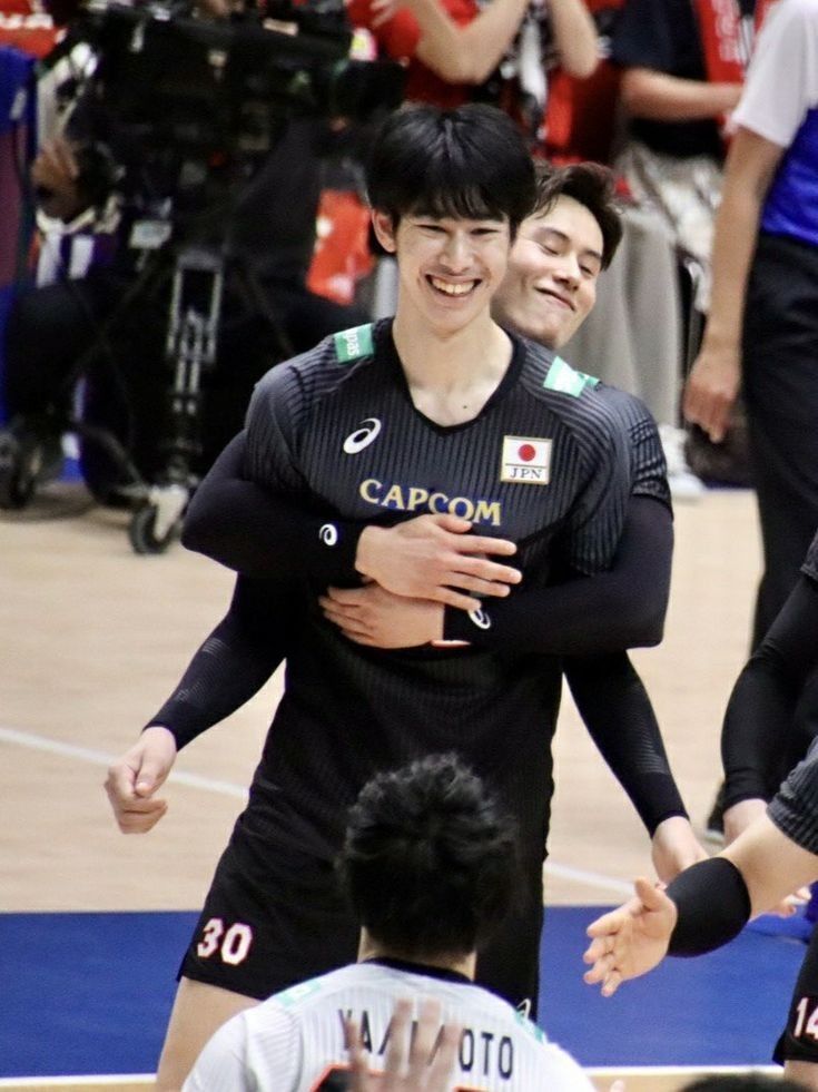 two men are hugging each other on the basketball court while people watch from behind them