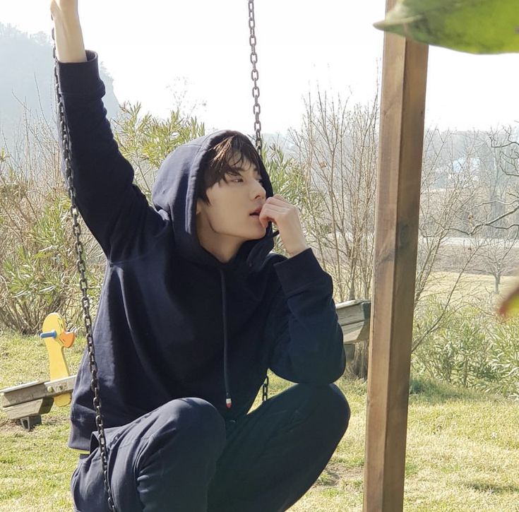 a young man sitting on top of a swing