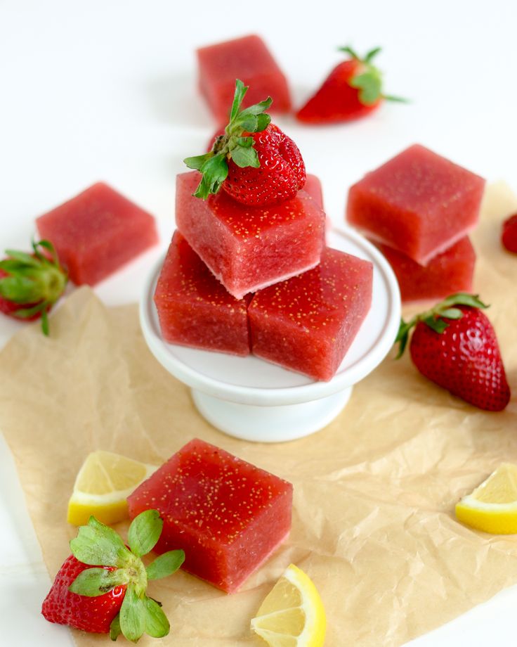 strawberries and lemons are arranged on wax paper next to sliced watermelon