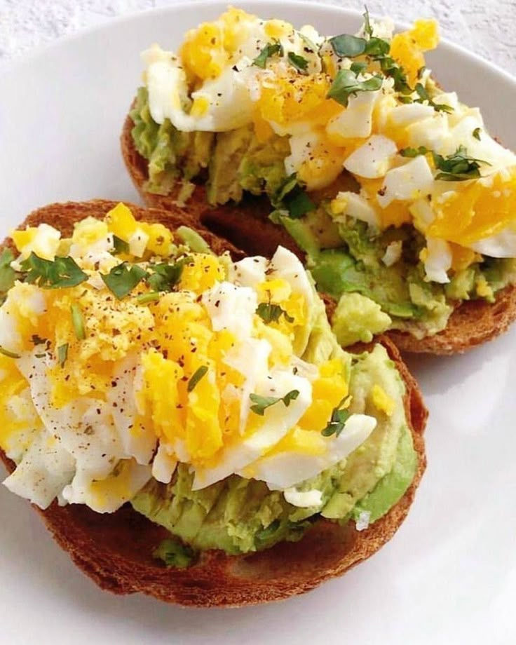 an open face sandwich with eggs, avocado and cheese on toasted bread